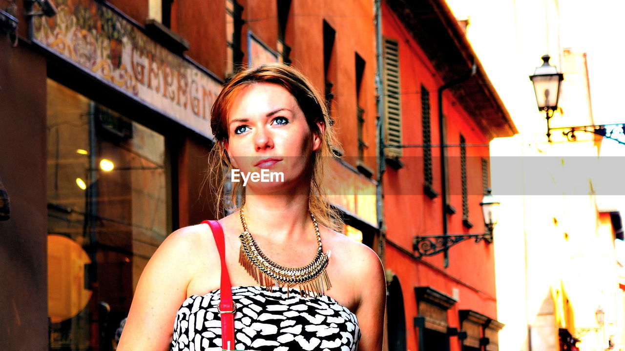 Beautiful woman standing against building in city