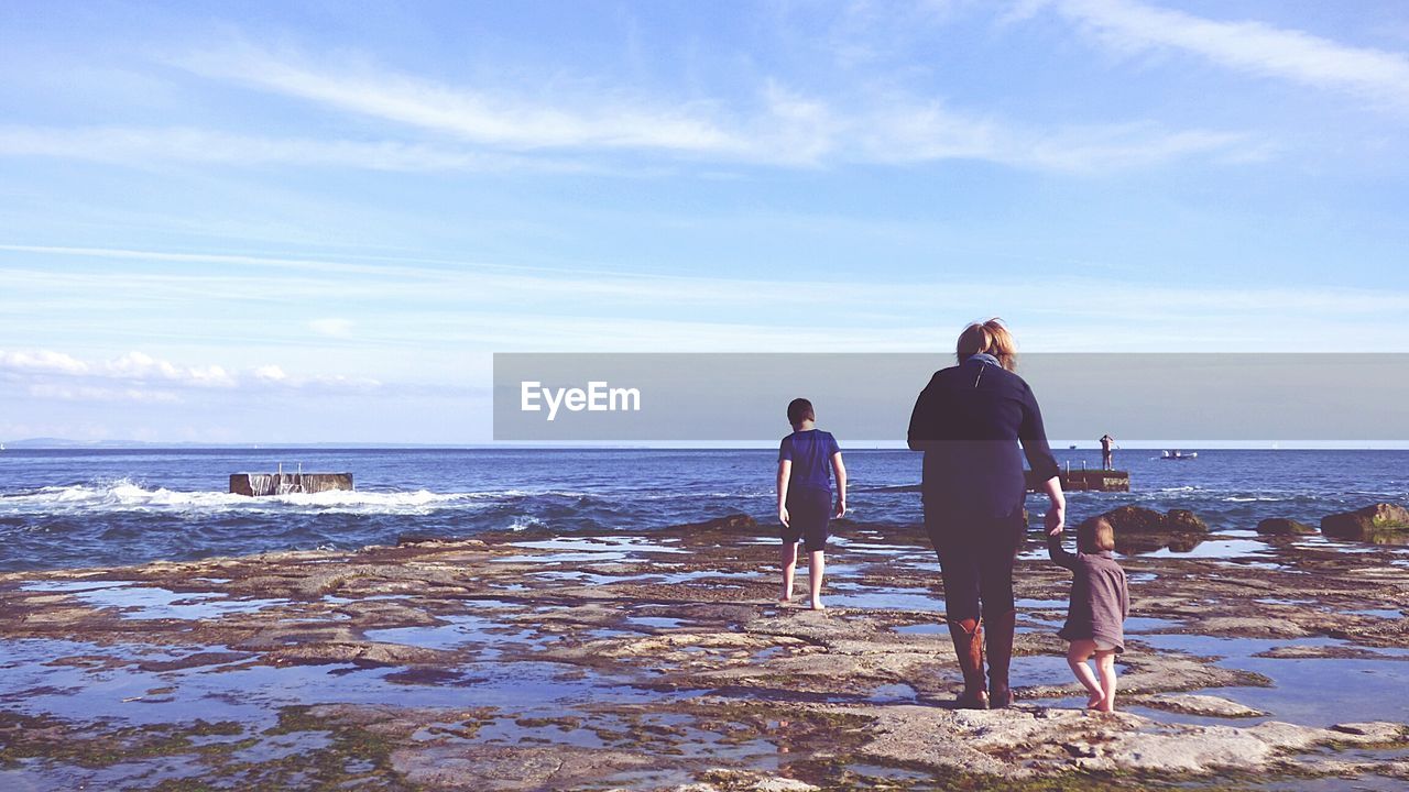 Rear view of woman with daughter and son at beach