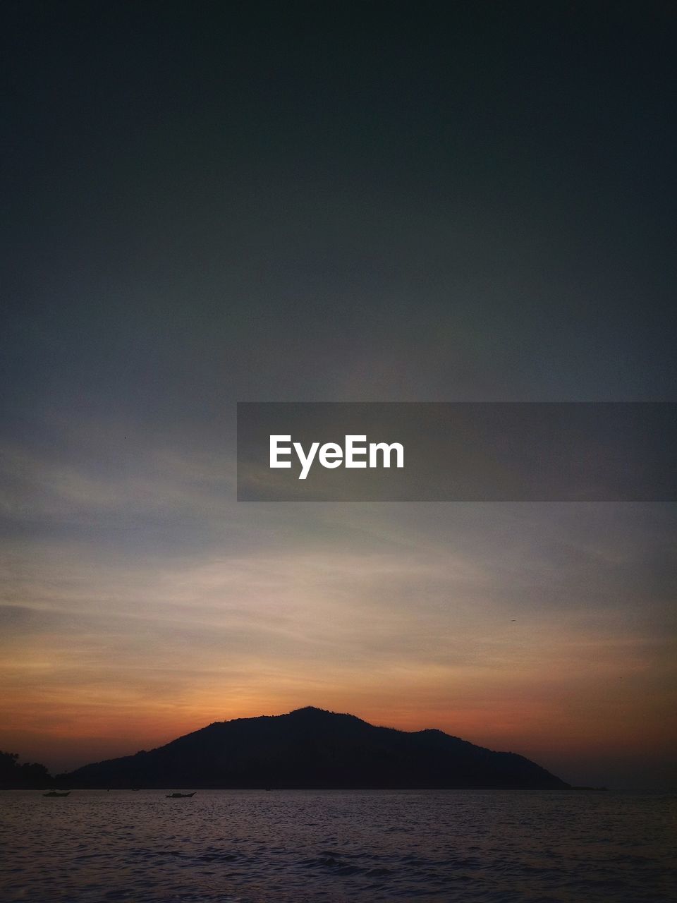SCENIC VIEW OF SEA BY SILHOUETTE MOUNTAIN AGAINST SKY