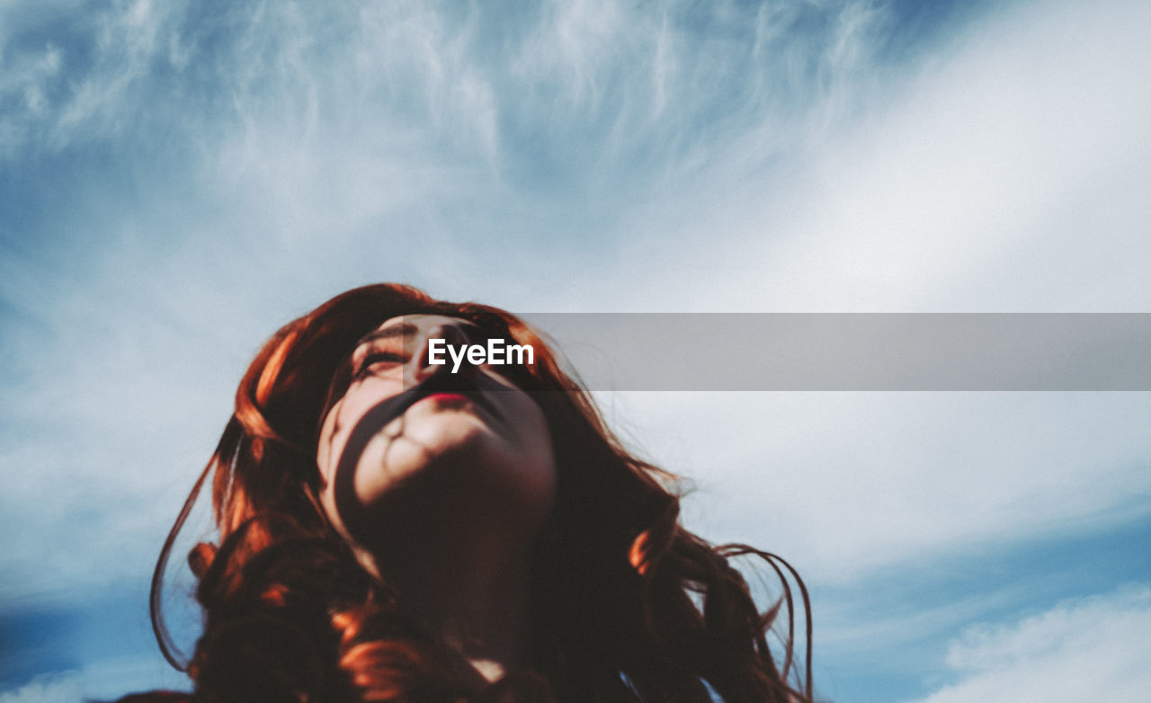 Low angle view of woman looking up against sky