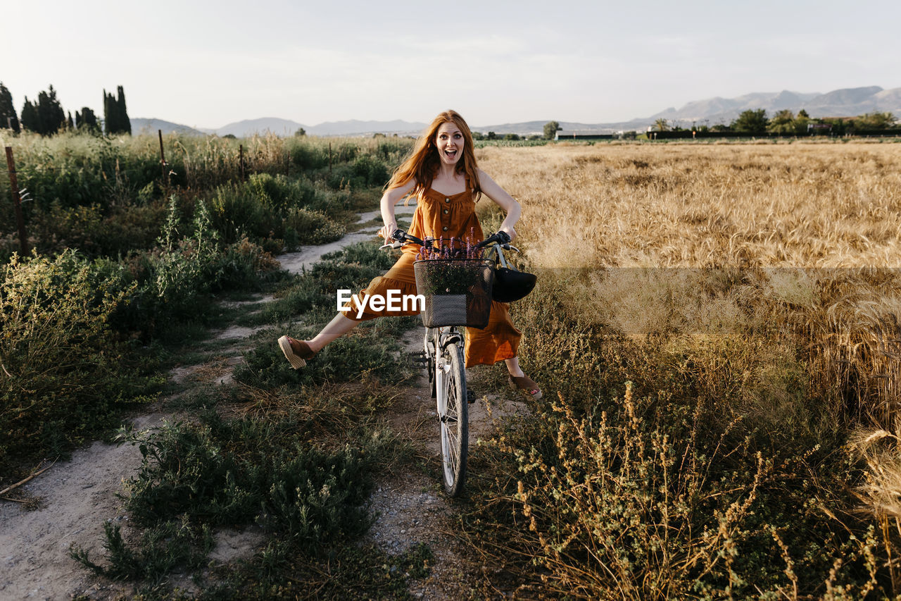 Carefree woman riding bicycle in agricultural field