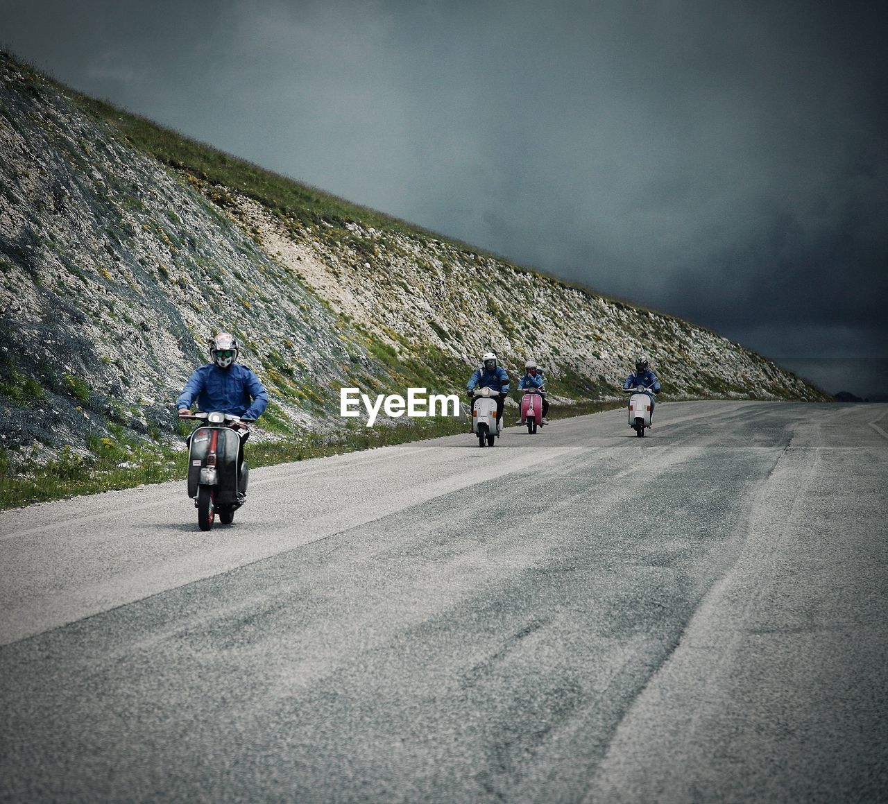 REAR VIEW OF PEOPLE RIDING BICYCLE ON ROAD