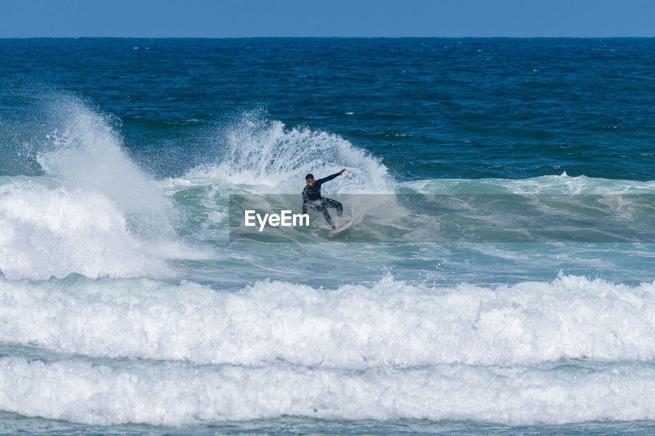 man surfing on sea against sky