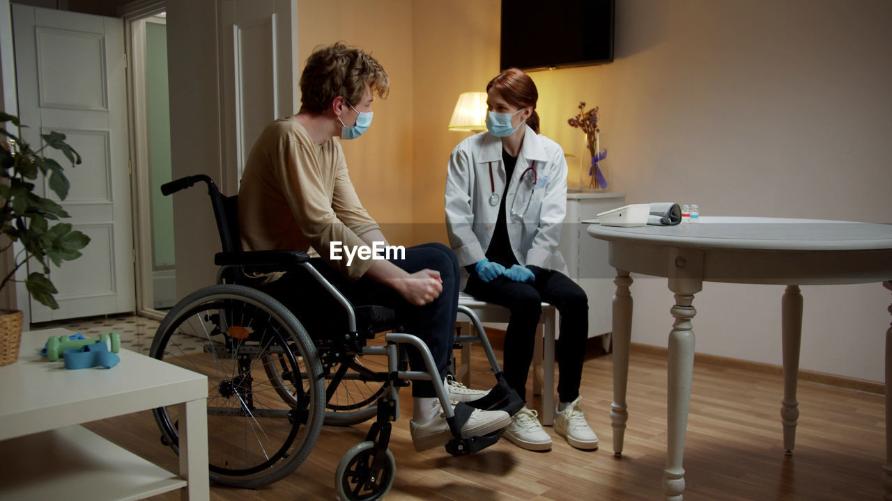 Doctor wearing mask examining patient at home