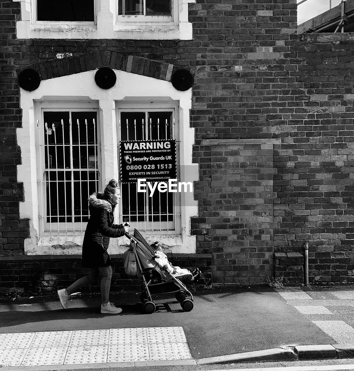 MAN WALKING ON STREET AGAINST BUILDING