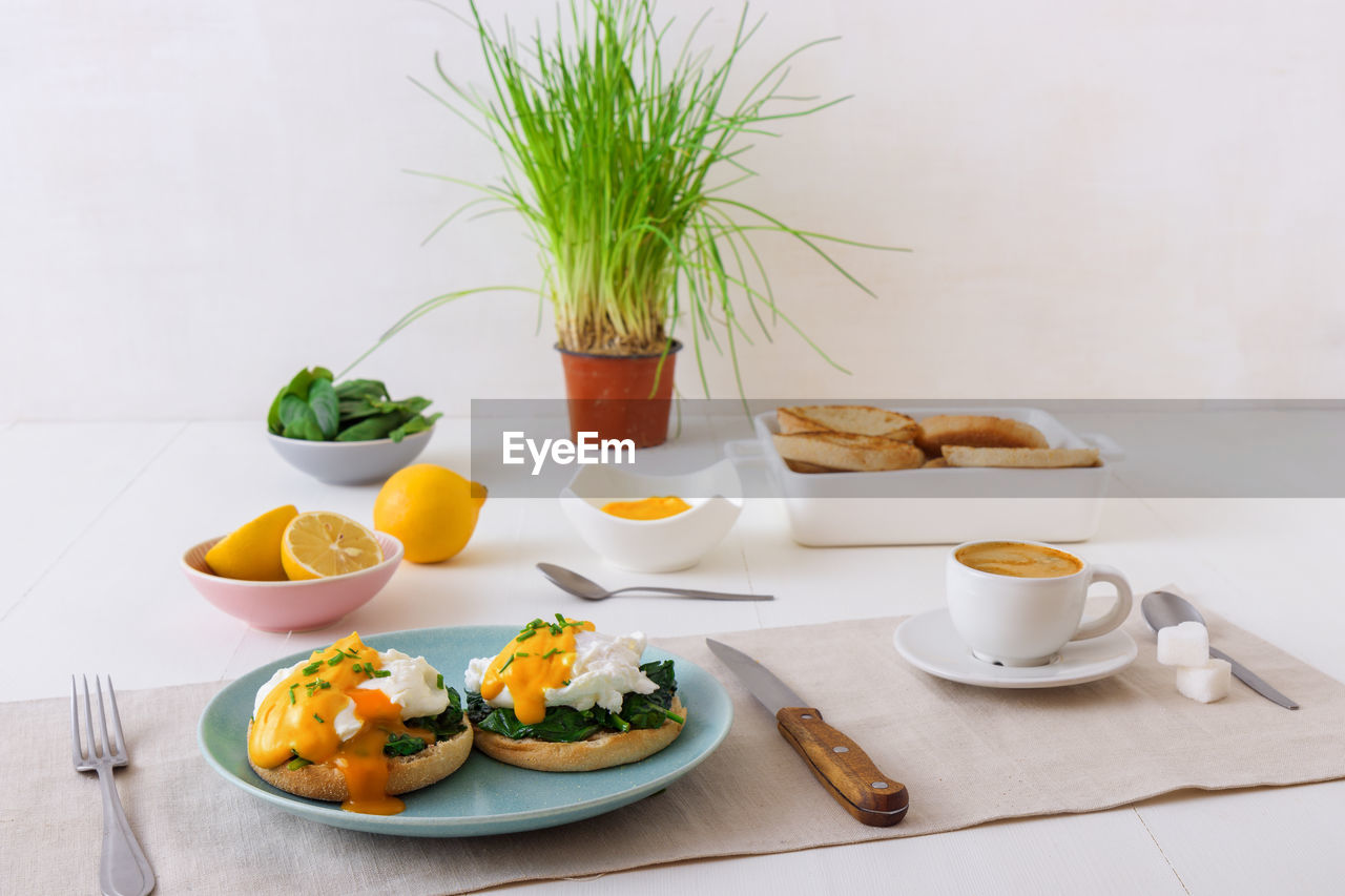 Eggs florentine, english muffins, poached eggs, mornay sauce, chive herbs, lemon, cup of coffee.