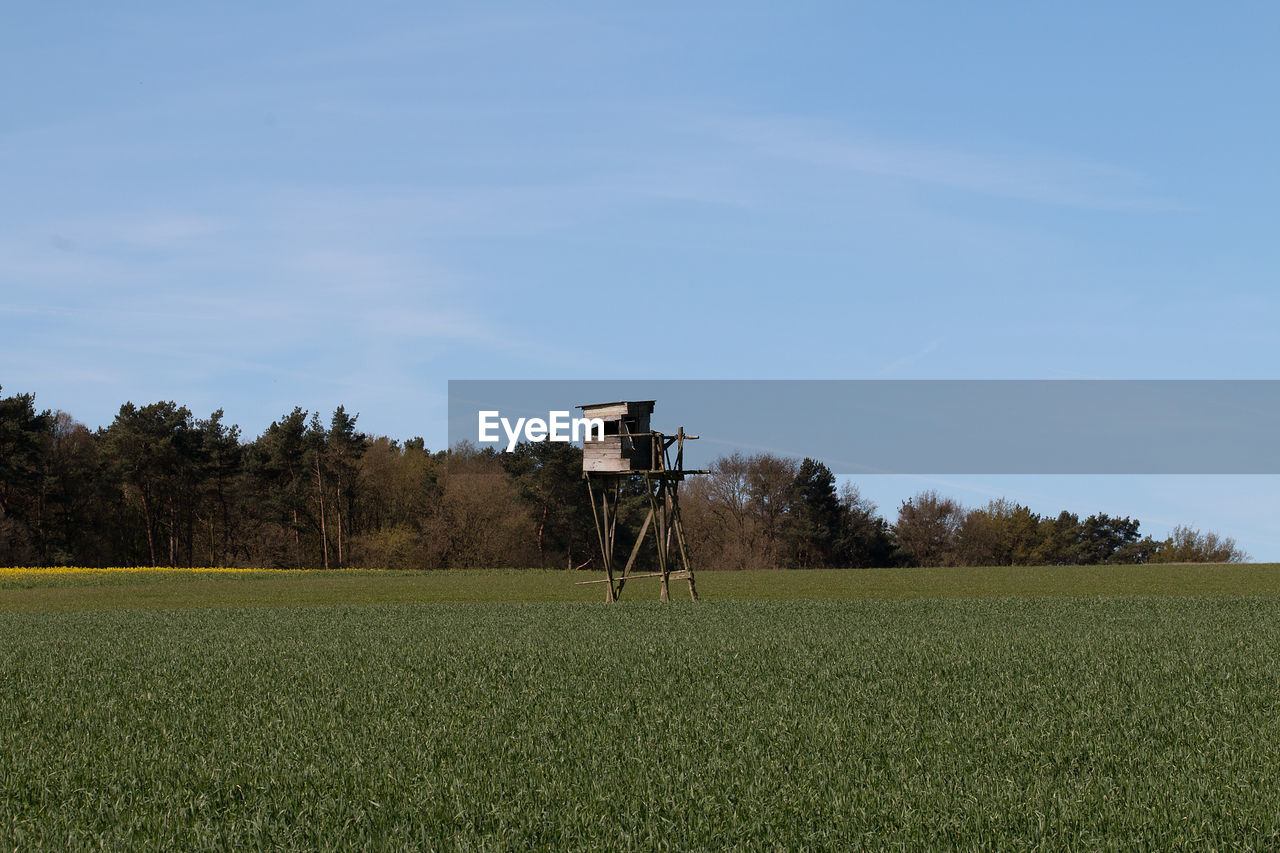 HUT ON FIELD AGAINST BLUE SKY