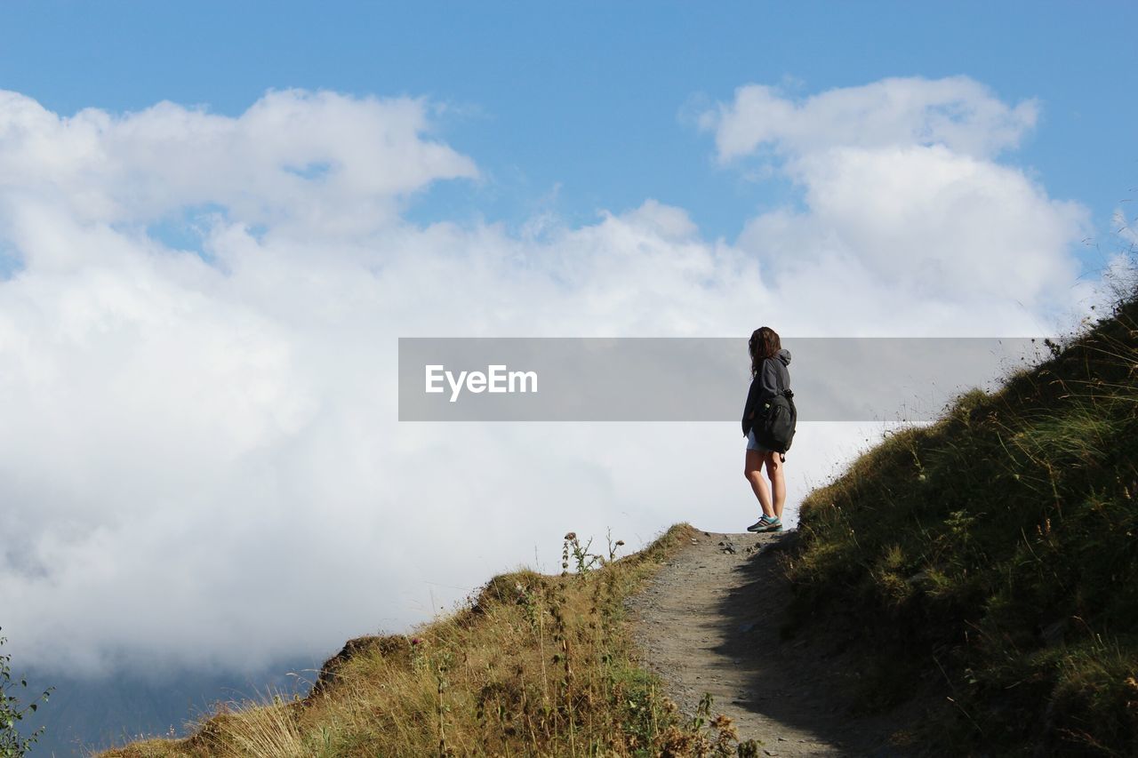 Full length of woman standing on mountain against cloudy sky