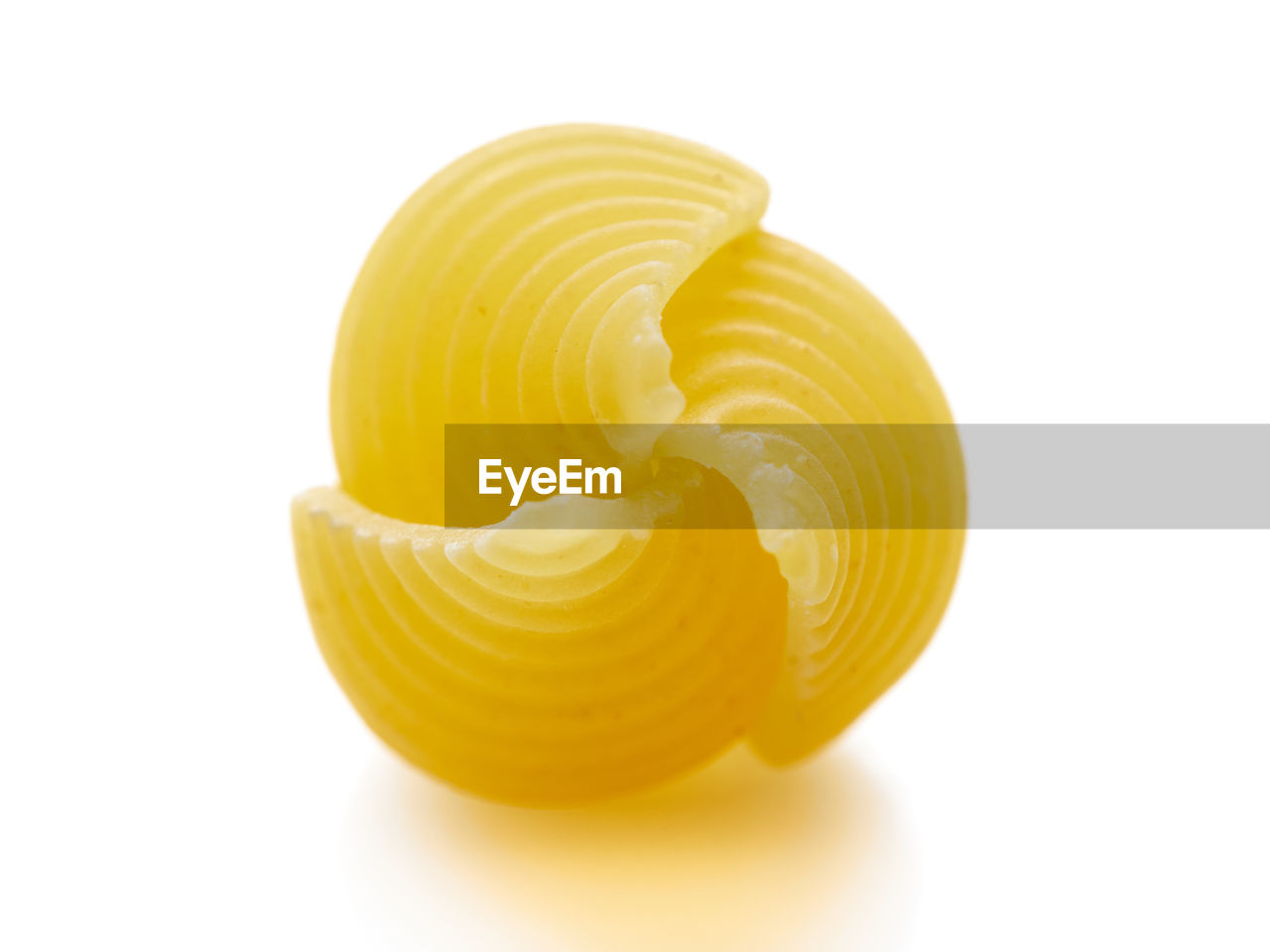 Close-up of yellow raw shell pasta against white background.