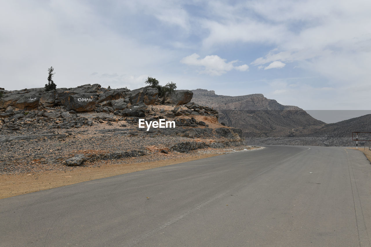 Road by desert against sky