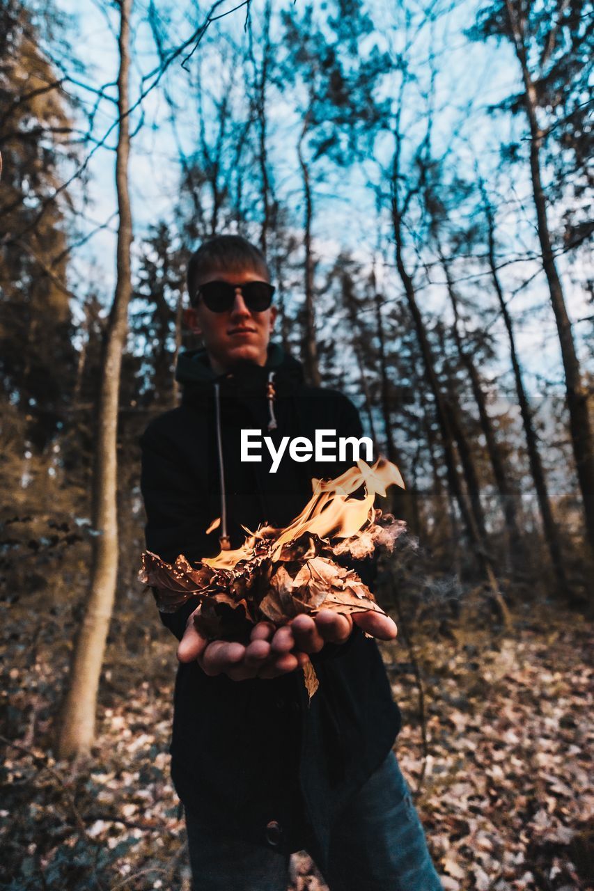 MAN HOLDING SUNGLASSES ON FOREST