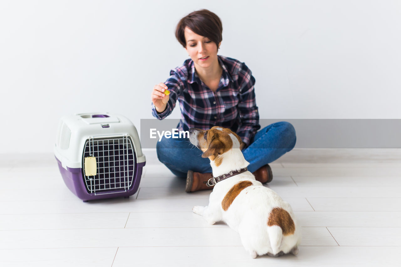 YOUNG WOMAN WITH DOG SITTING ON FLOOR