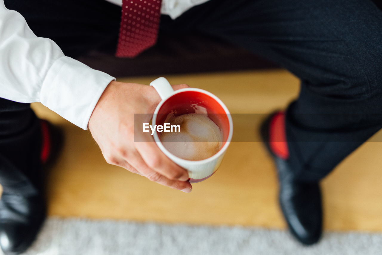 Low section of businessman having coffee while sitting on seat