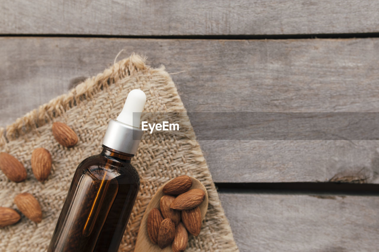 Almond essential oil in glass bottle with spoon. cosmetic concept on wooden background