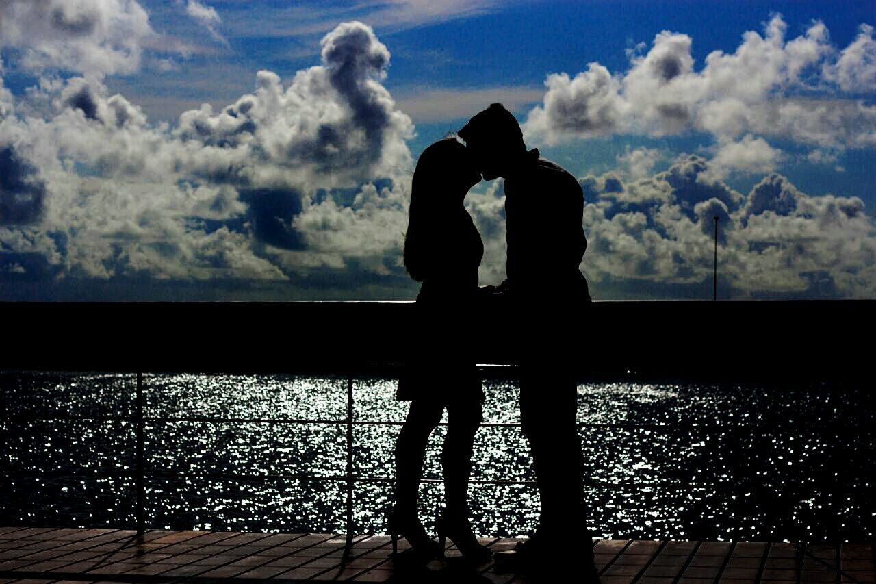 Silhouette couple kissing by sea