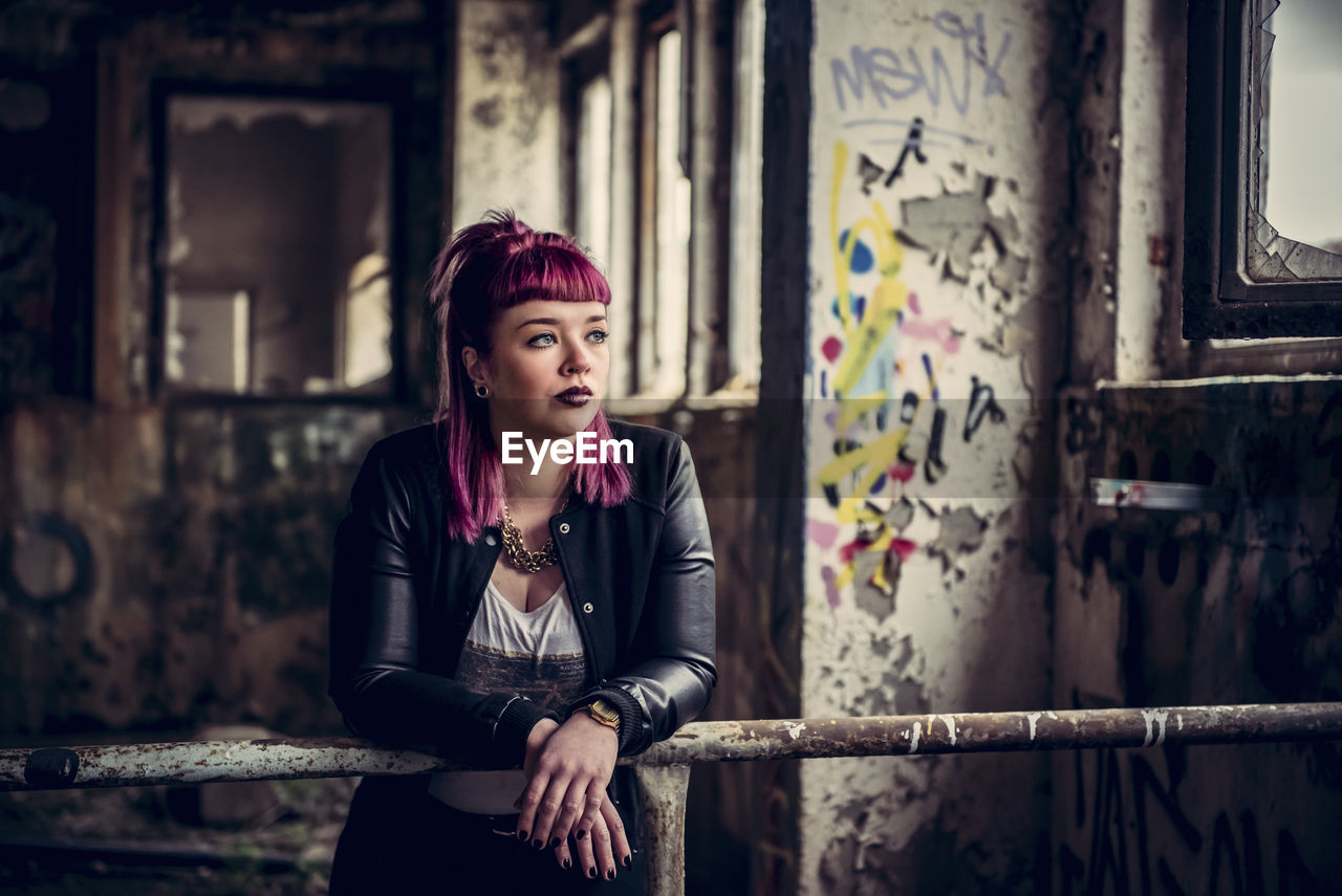 Thoughtful young woman leaning on railing in abandoned building