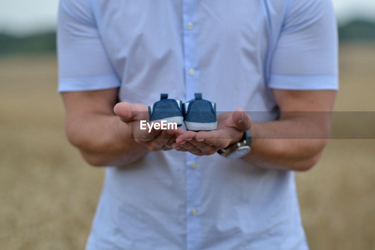 Father's hand holding blue baby shoes