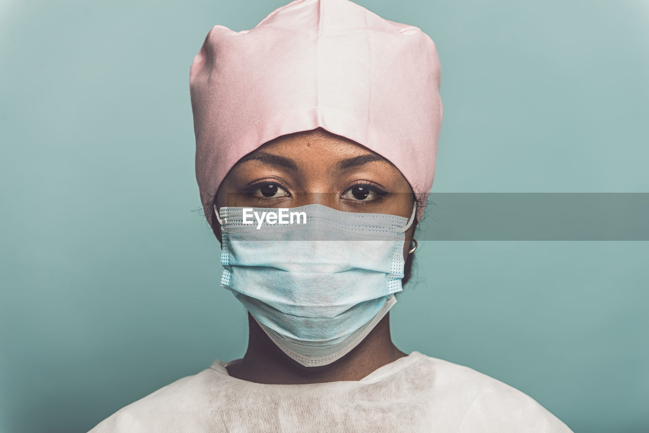 Portrait of doctor standing against colored background