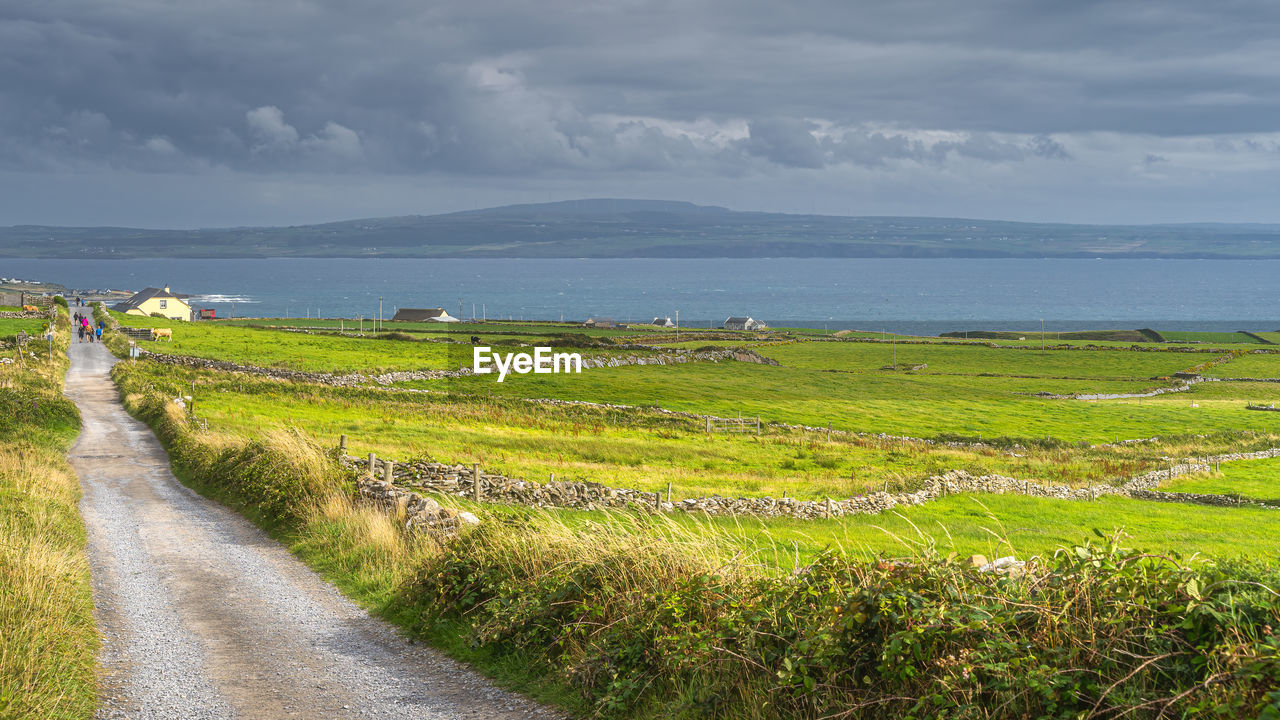 Tourists walking down the country road from iconic cliffs of moher, ireland