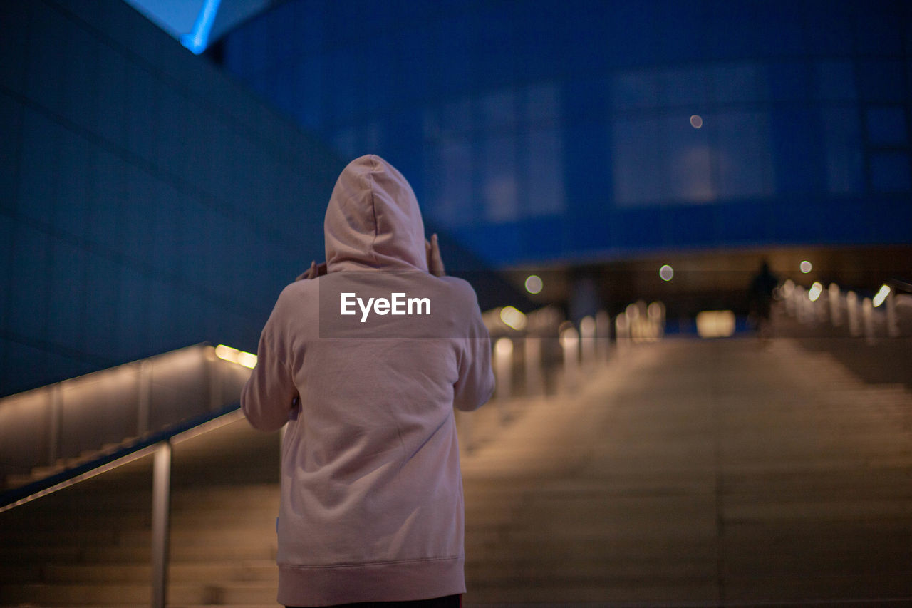 Rear view of person standing on staircase at night