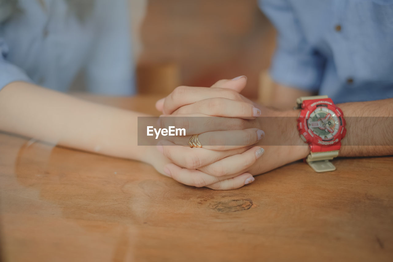 Midsection of couple holding hands at table