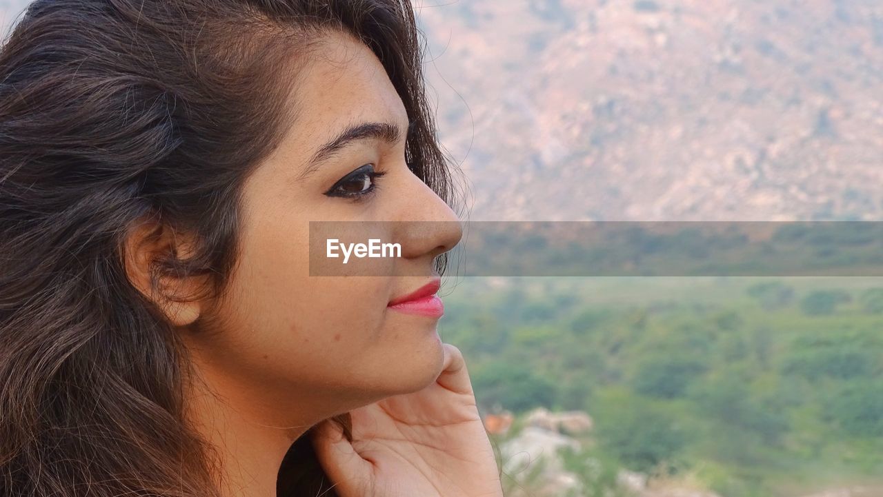 Close-up side view of smiling young woman looking away