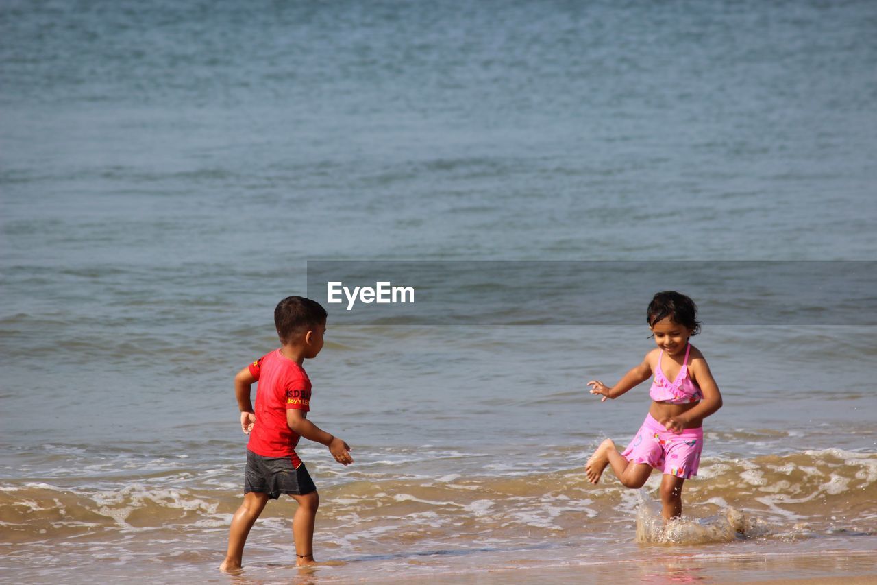 Happy siblings playing on shore at beach