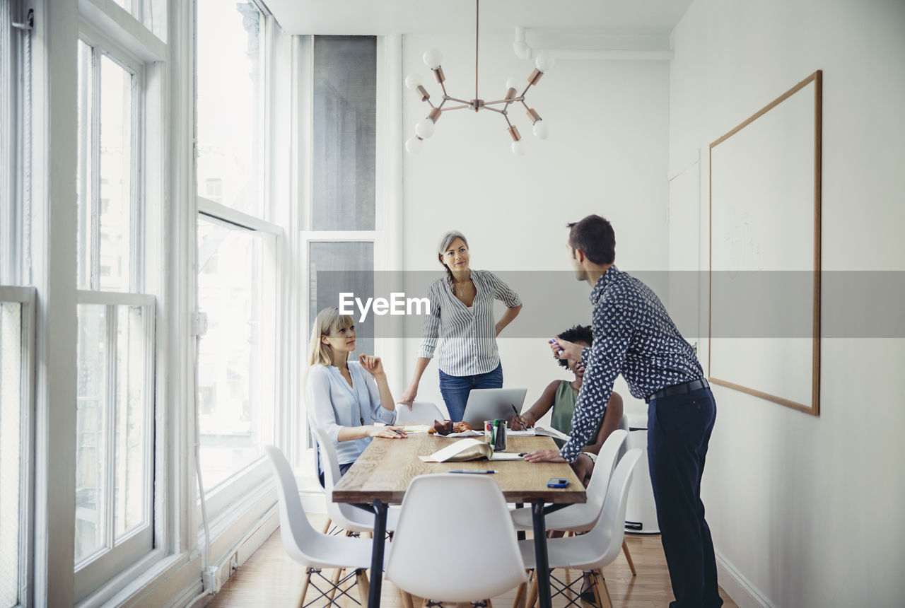 Businessman explaining strategy to female colleagues in board room