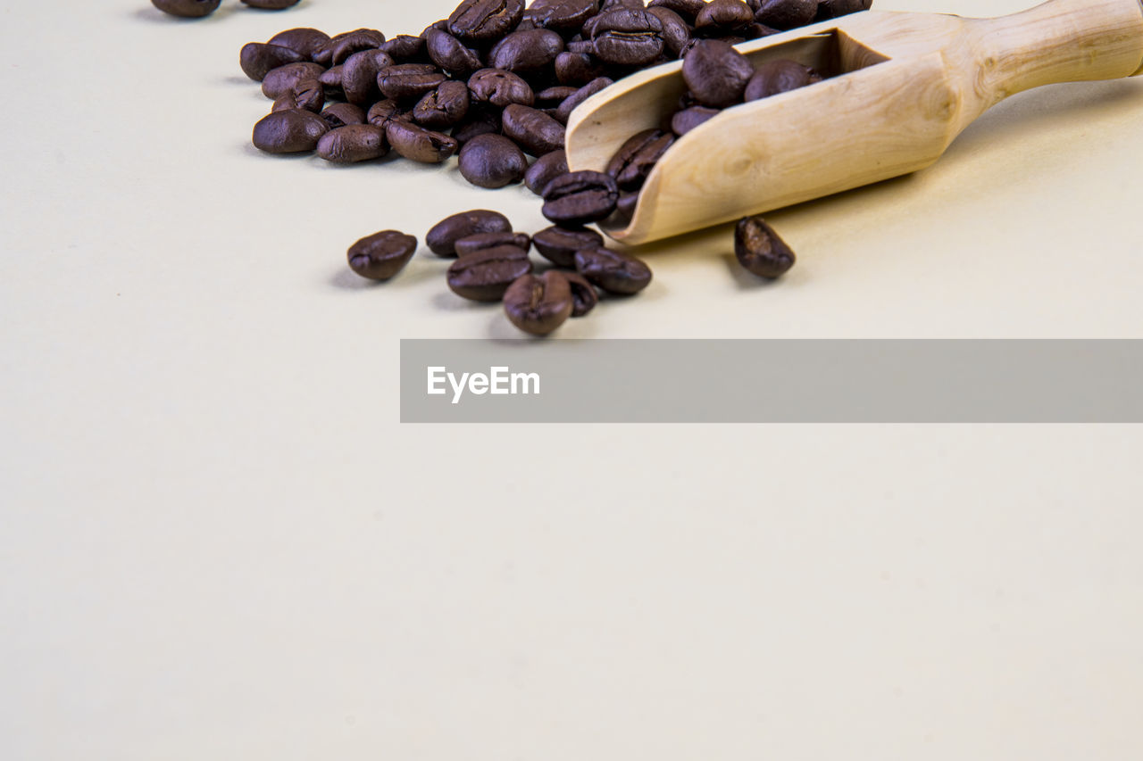 HIGH ANGLE VIEW OF COFFEE BEANS ON WHITE TABLE
