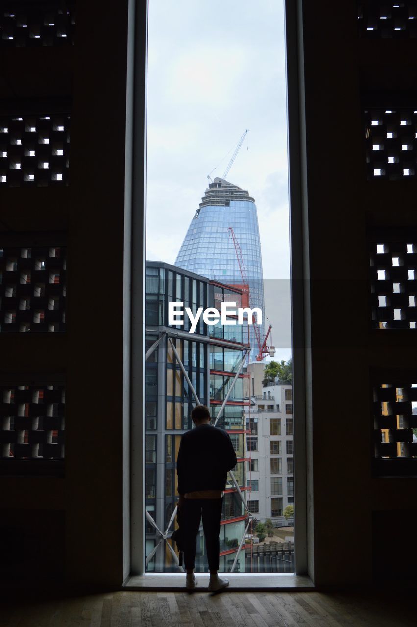 REAR VIEW OF MAN IN MODERN OFFICE BUILDING