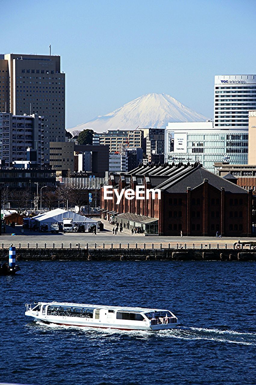 Passenger craft in river with cityscape and mt fuji in background