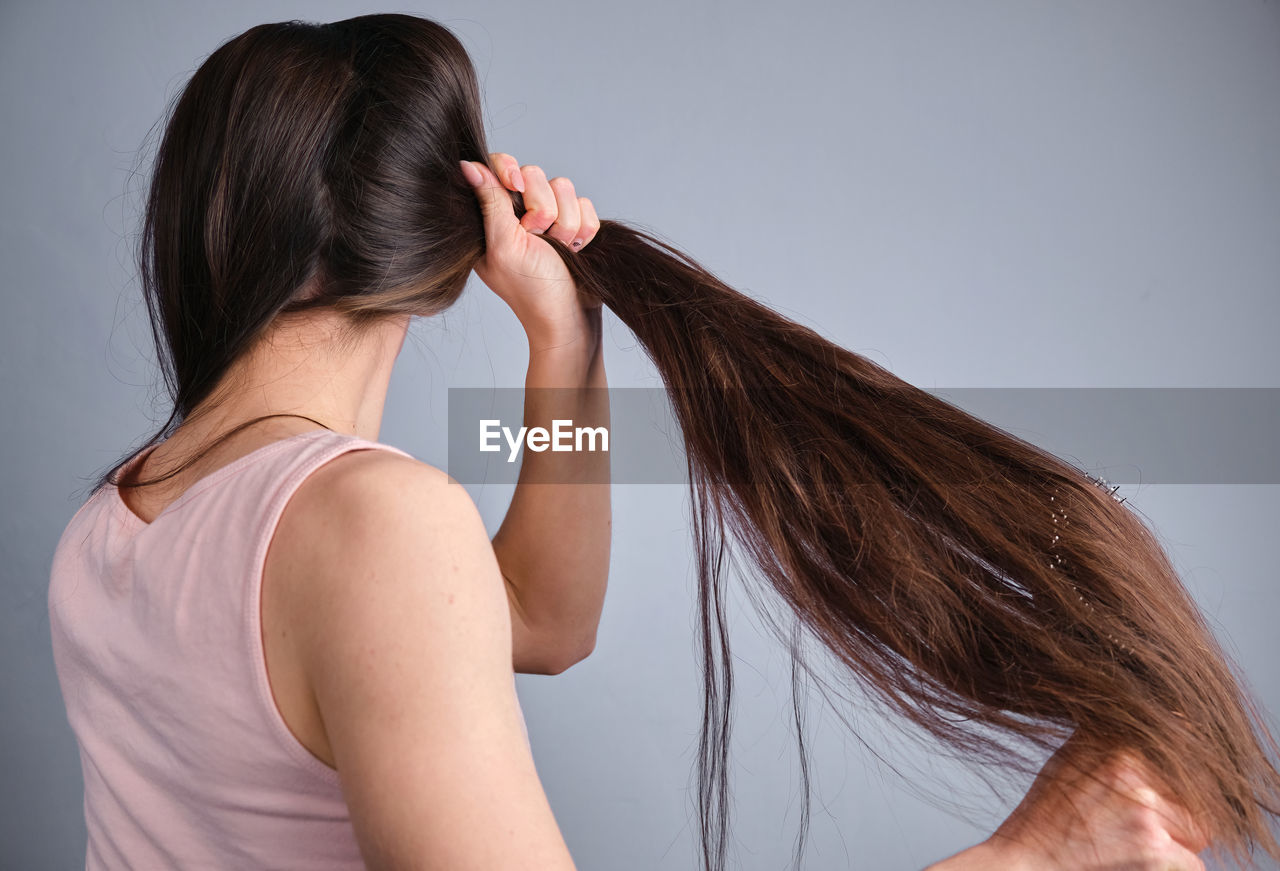 adult, human hair, hairstyle, women, long hair, brown hair, rear view, one person, young adult, studio shot, indoors, hair care, portrait, photo shoot, arm, body care, female, lifestyles, headshot, gray background, person, emotion, black hair, gray, back, hair color, waist up