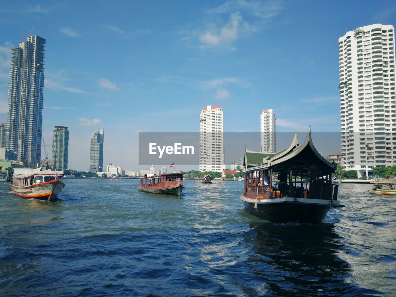 BOATS SAILING IN SEA AGAINST BUILDINGS IN CITY