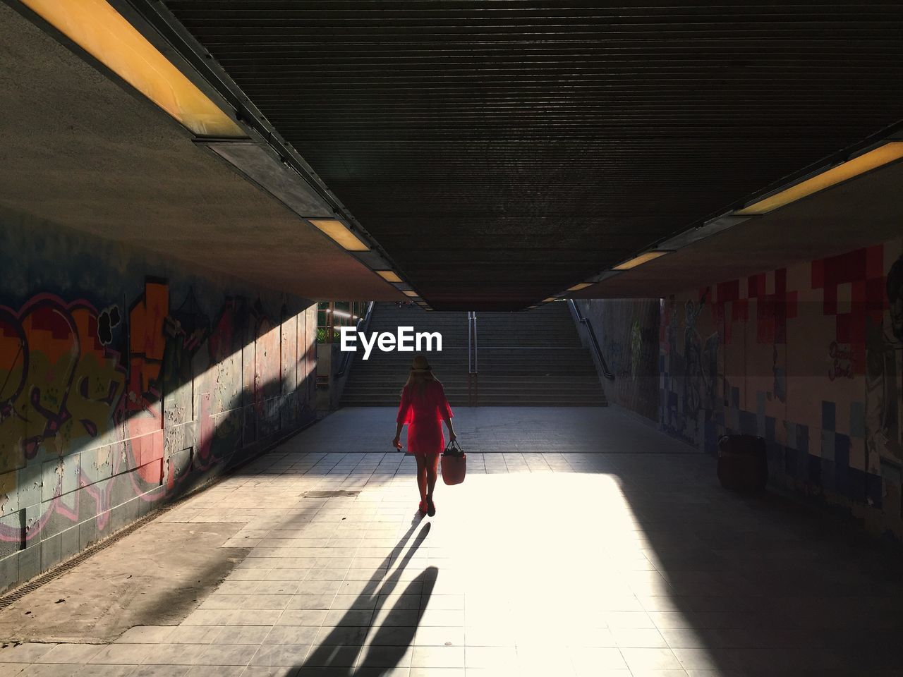 REAR VIEW OF WOMAN WALKING ON CORRIDOR OF BUILDING