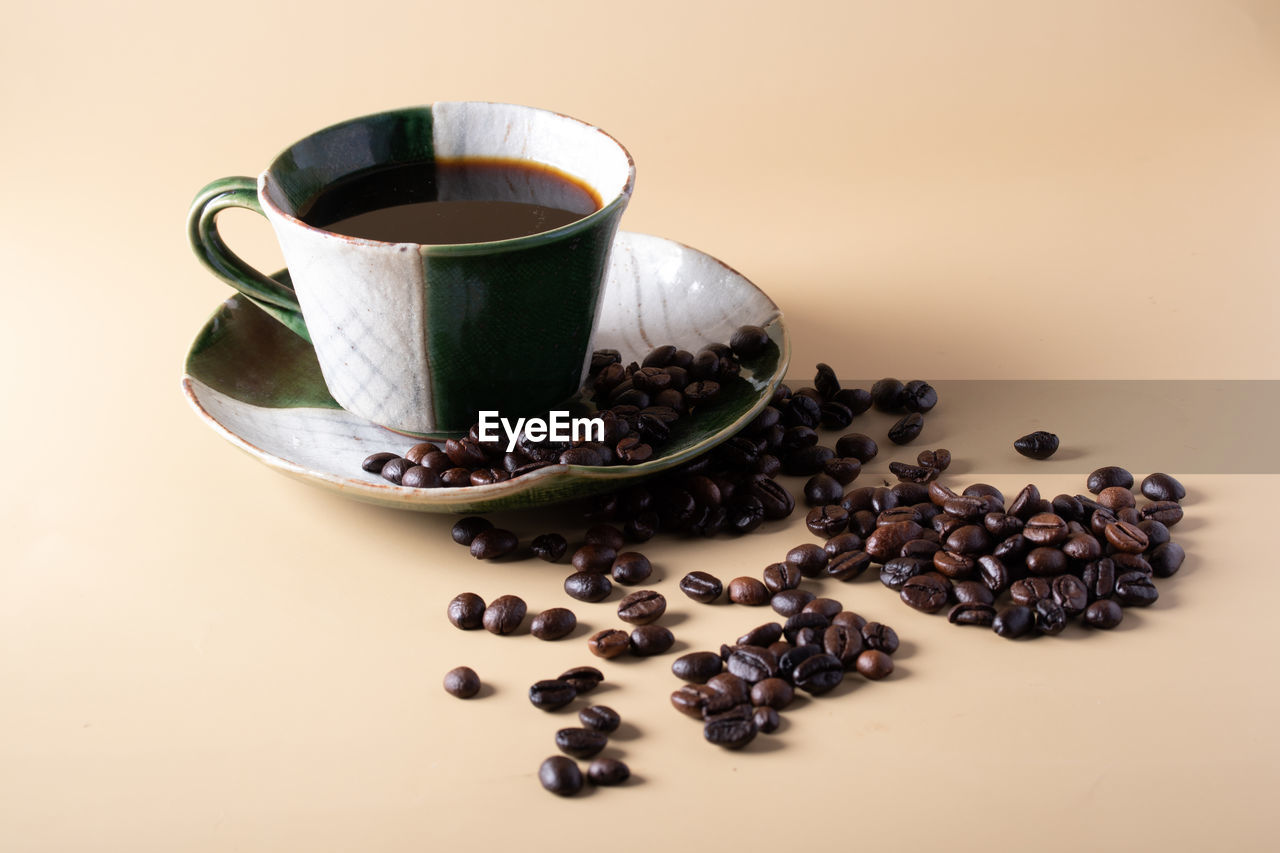 CLOSE-UP OF COFFEE CUP ON TABLE AGAINST WALL