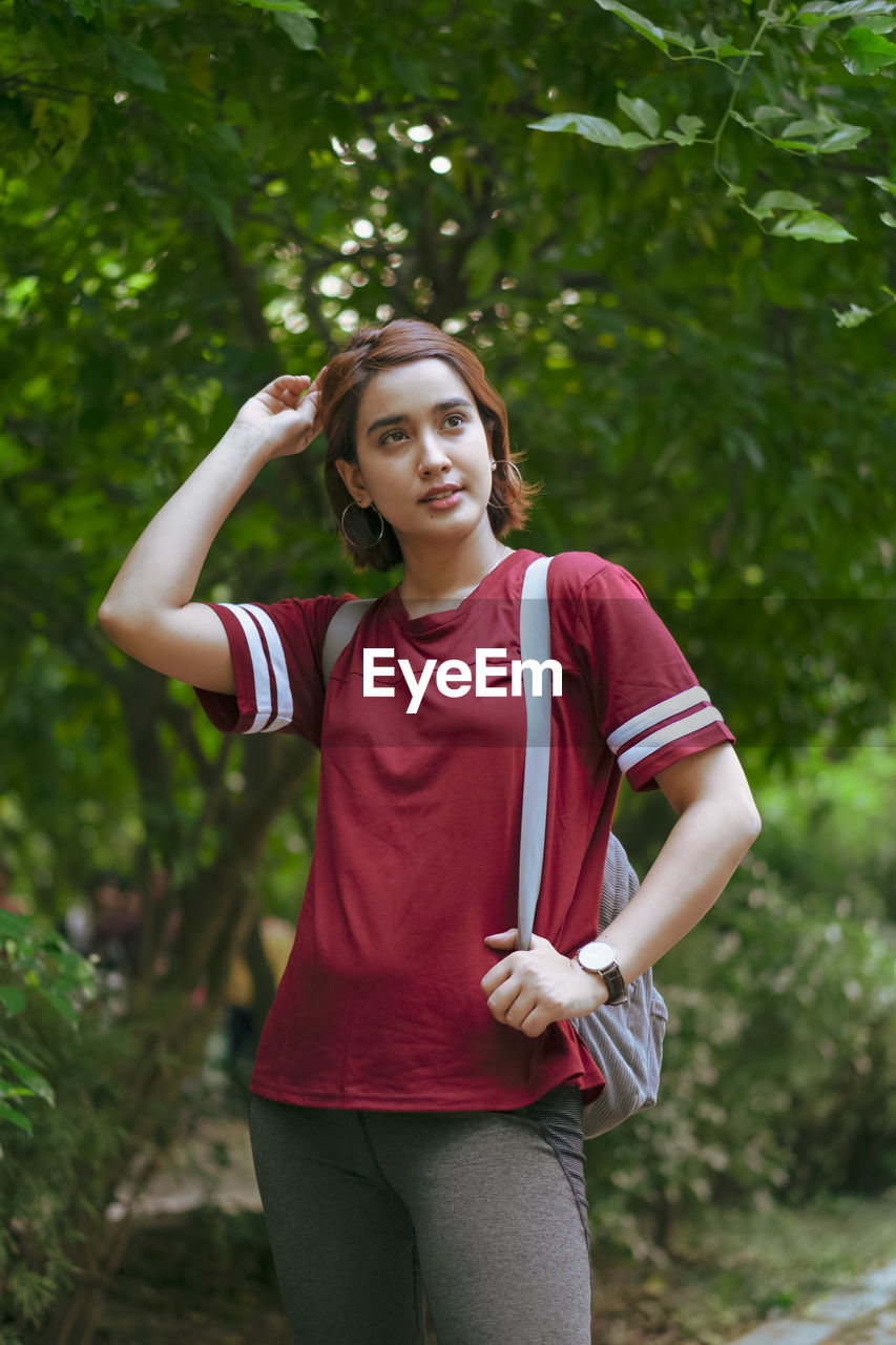 Young woman standing against trees