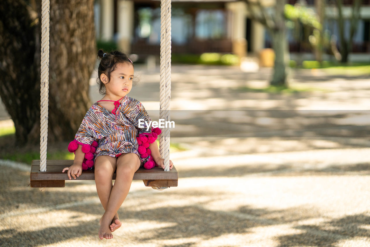 GIRL SITTING ON PLAYGROUND