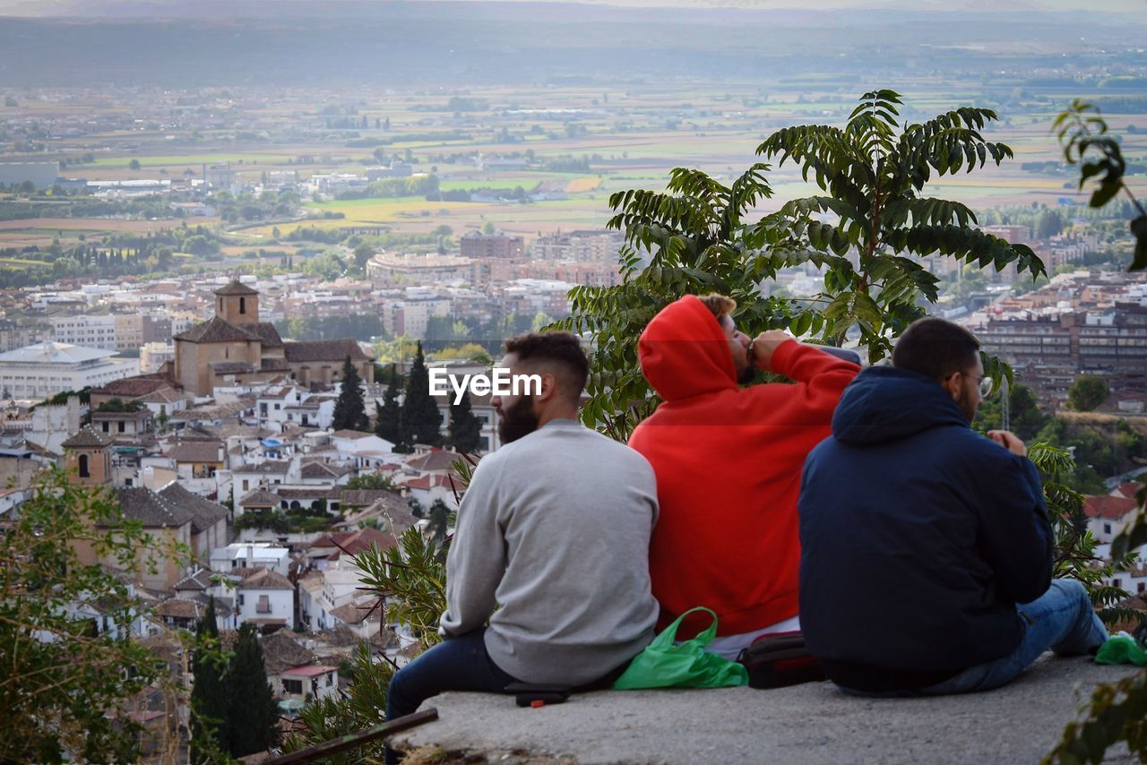 REAR VIEW OF MAN LOOKING AT CITY