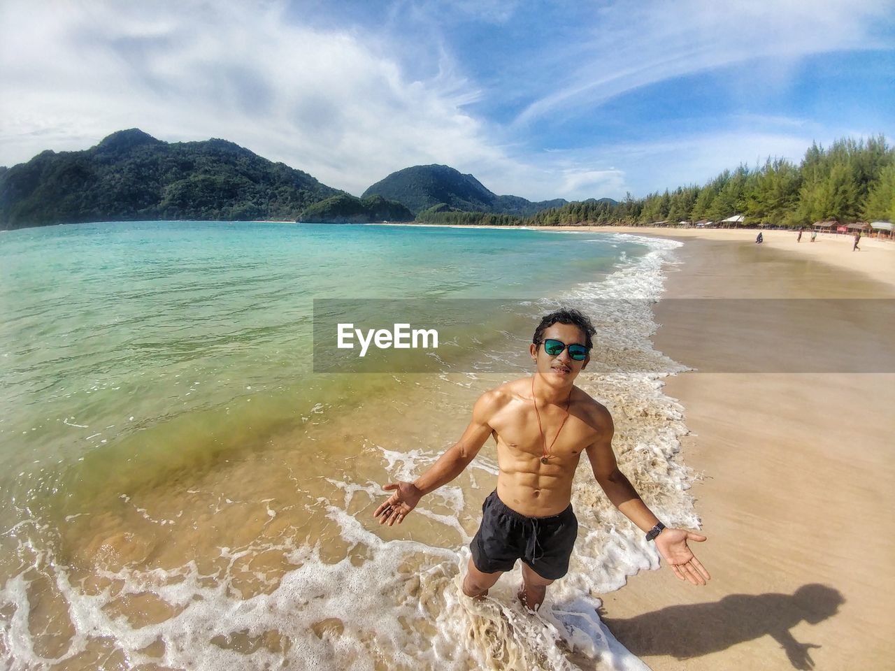 Full length of shirtless man at beach against sky