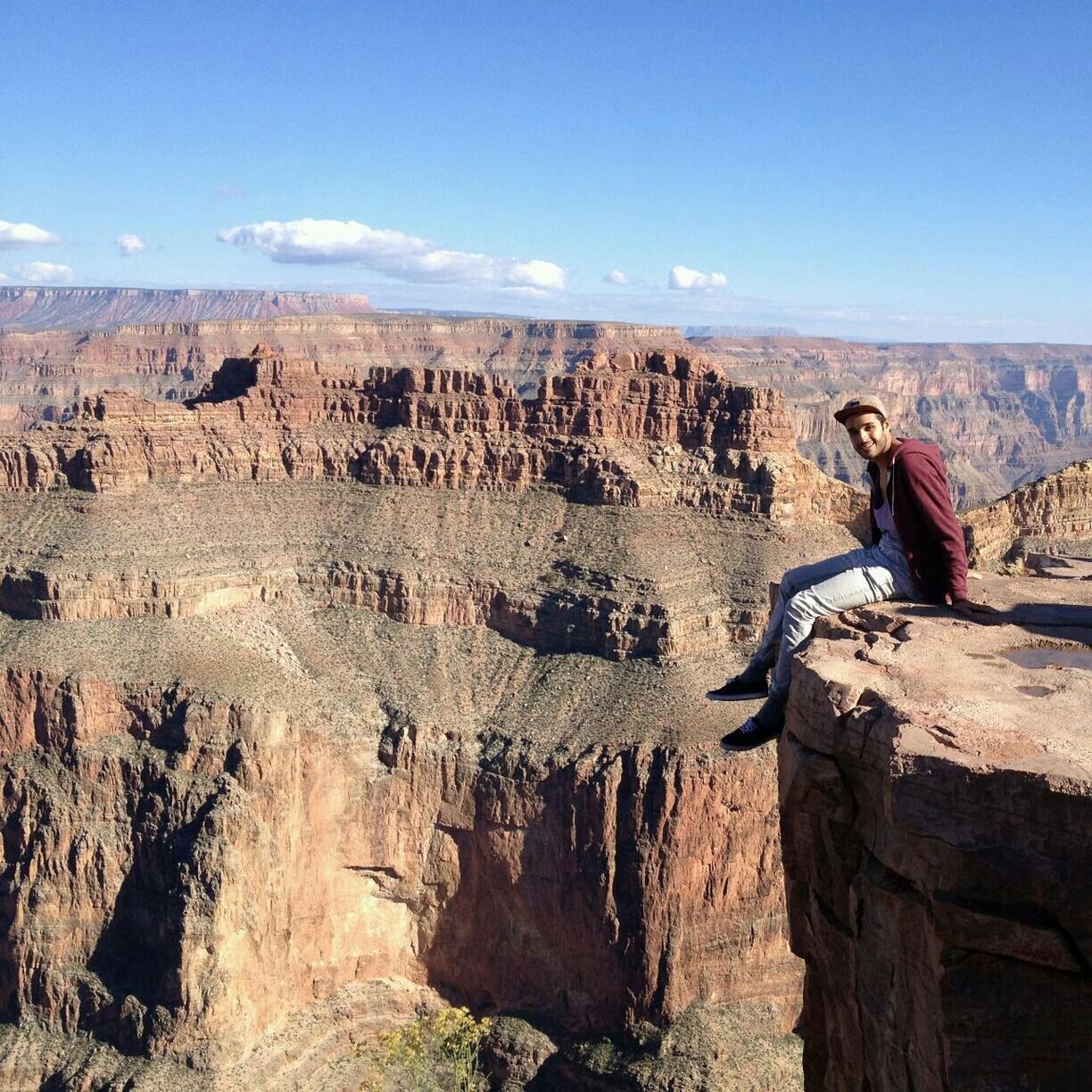 Scenic view of young man sitting on precipice