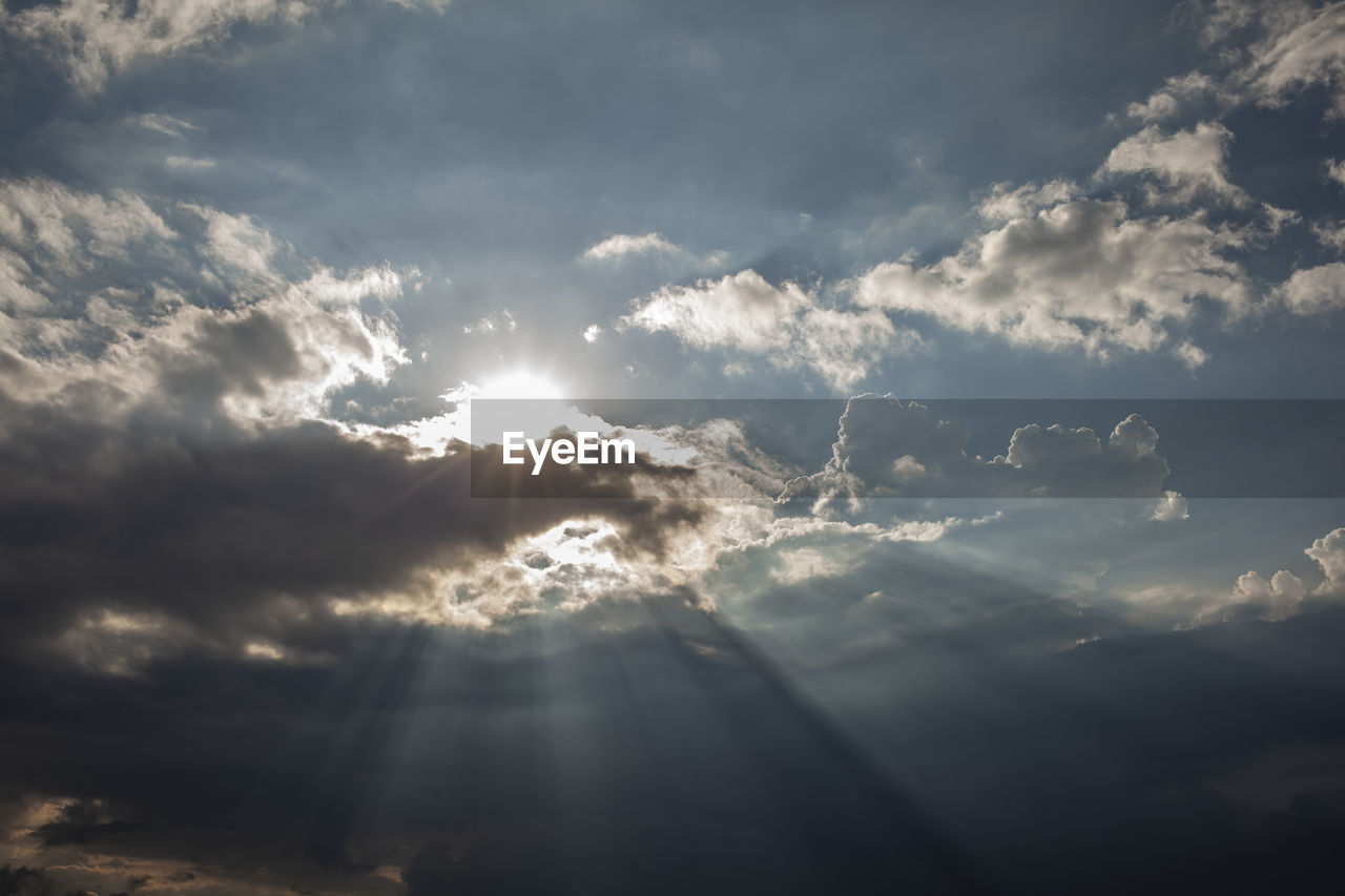 Moody cumulus clouds with sunbeams in the sky