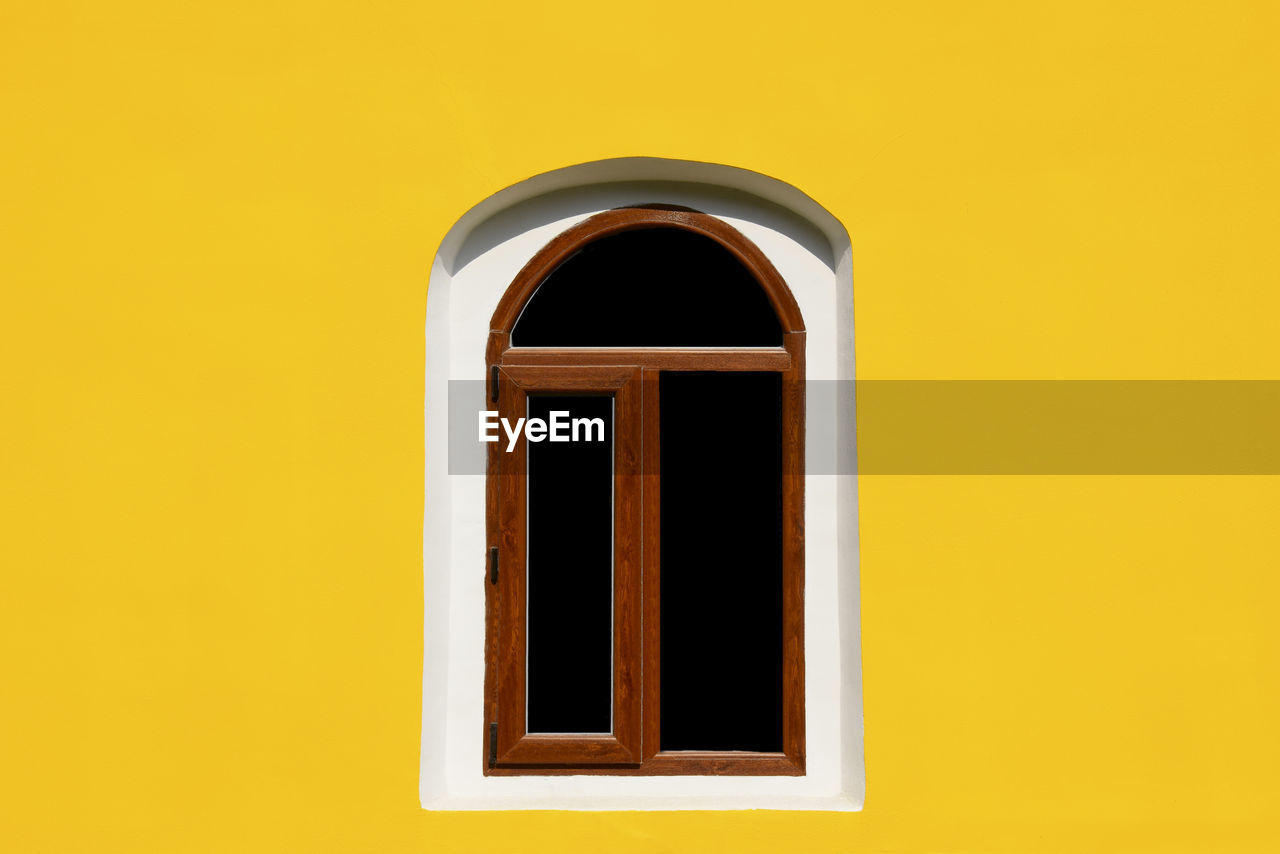 One arch window on yellow wall of old house. empty place for text. close-up.