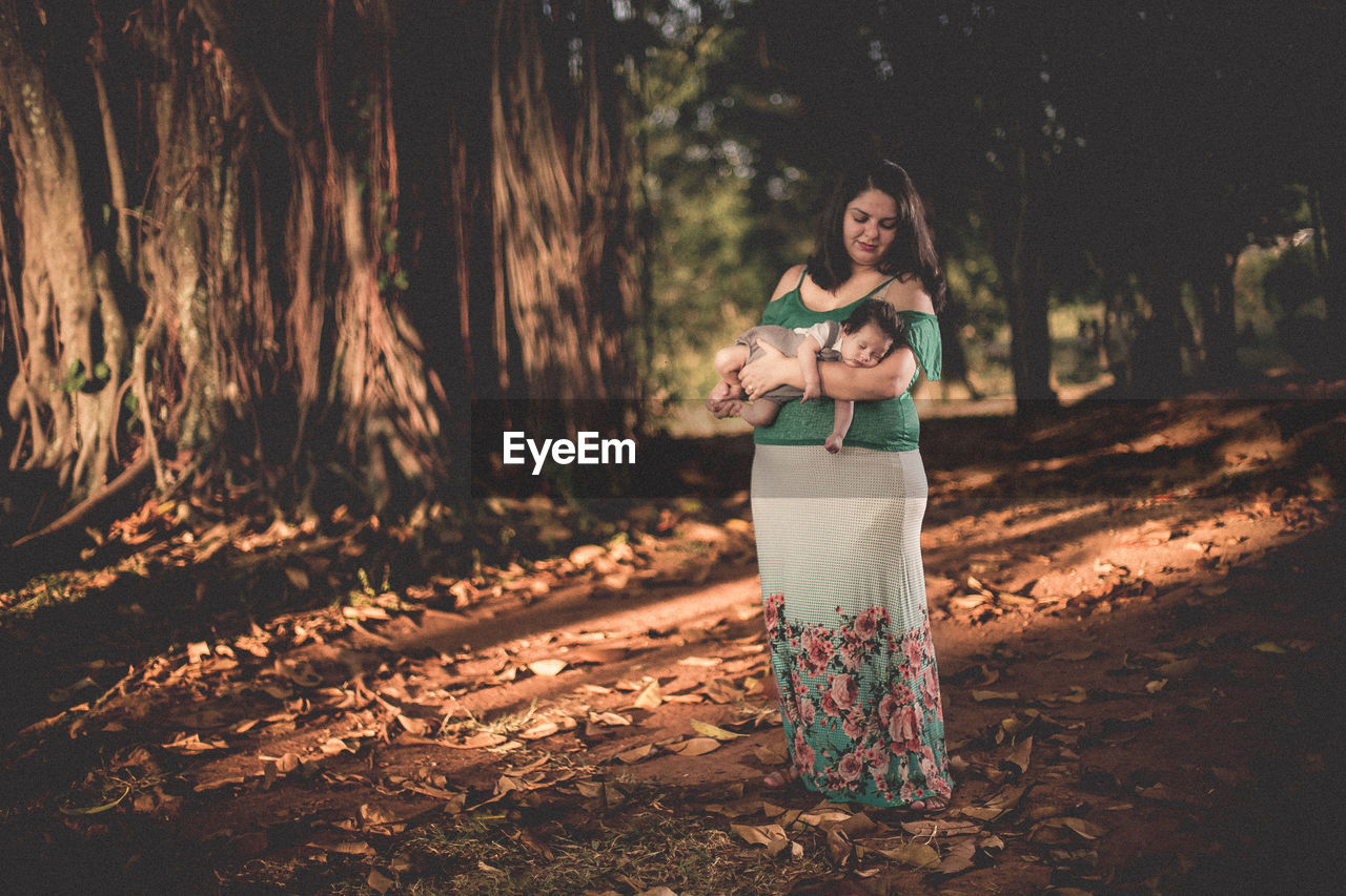 Full length of woman standing by tree in forest