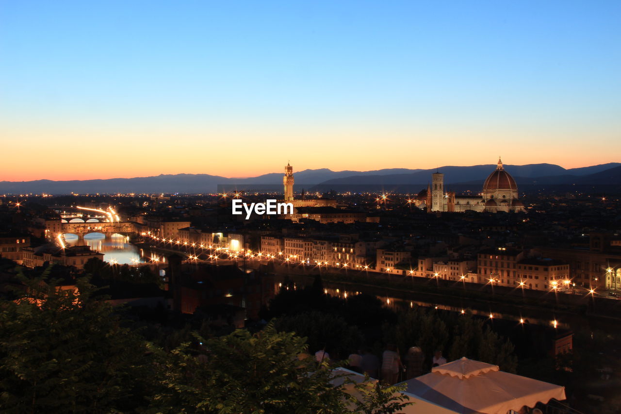 Illuminated city against clear sky at dusk