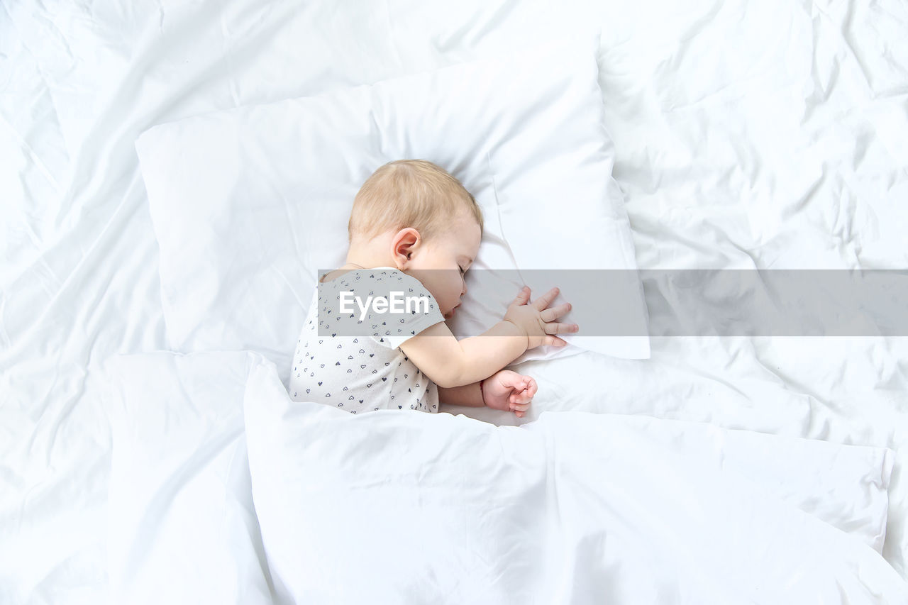 High angle view of baby girl sleeping on bed at home