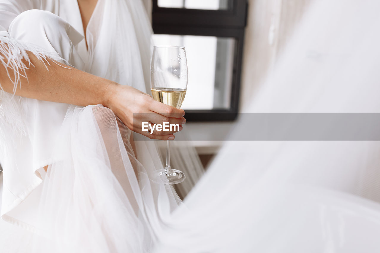 midsection of bride and groom holding bouquet