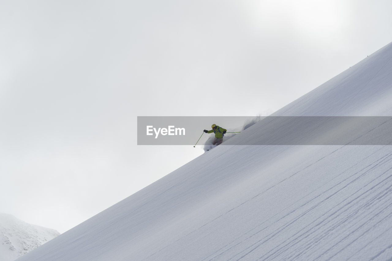 Low angle view of man skiing on snowcapped mountain against sky