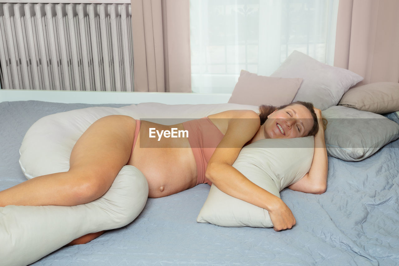 low section of woman lying on bed at home