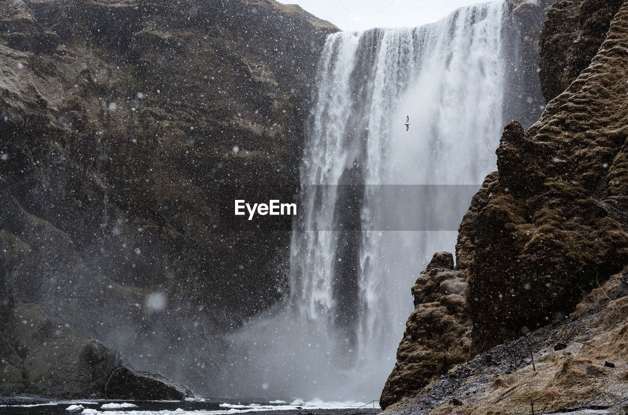 SCENIC VIEW OF WATERFALL AGAINST MOUNTAIN