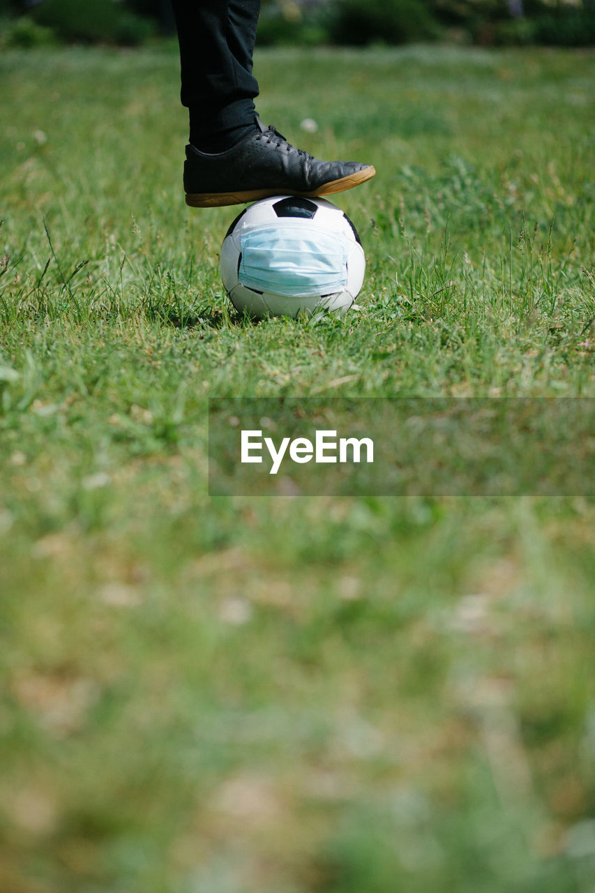 Food ready to kick off soccer football with surgical face mask on natural turf grass, 